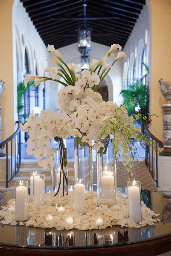 a tall wedding centerpiece of white orchids, callas and hydrangeas surrounded with candles is amazing for a formal wedding