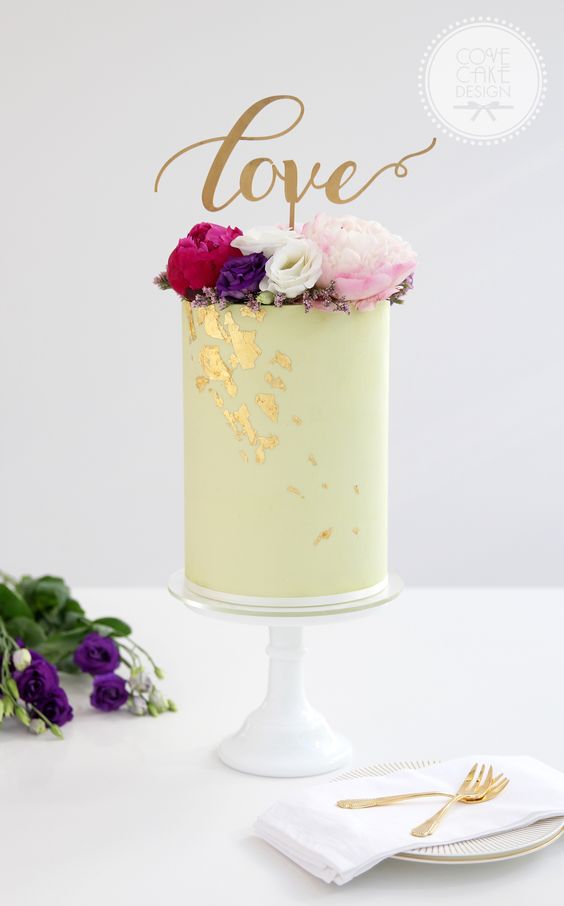 a tall yellow wedding cake with gold leaf, bold blooms and a calligraphy topper for a bright wedding