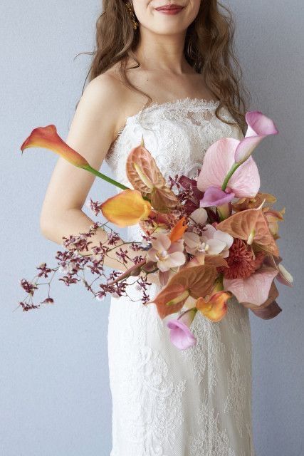 a whimsical wedding bouquet of light pink and peachy callas, anthuriums, foliage, orchids and mums is amazing