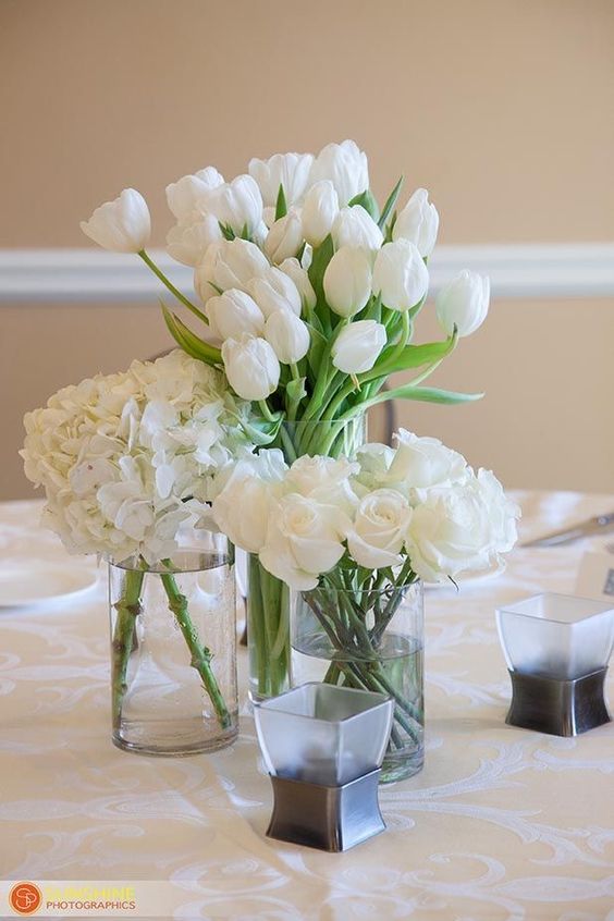 a white cluster wedding centerpiece of tulips, roses and hydrangeas is a cool solution for a modern white or neutral wedding