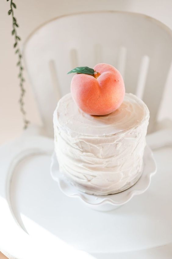 a white textred wedding cake topped with a single peach is a cool idea for a summer wedding