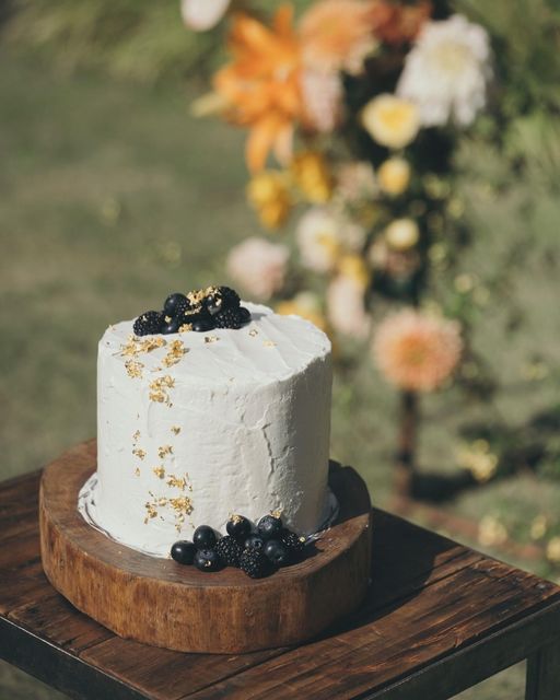 a white textured wedding cake decorated with blackberries and blueberries plus gold foil is delicious for the fall