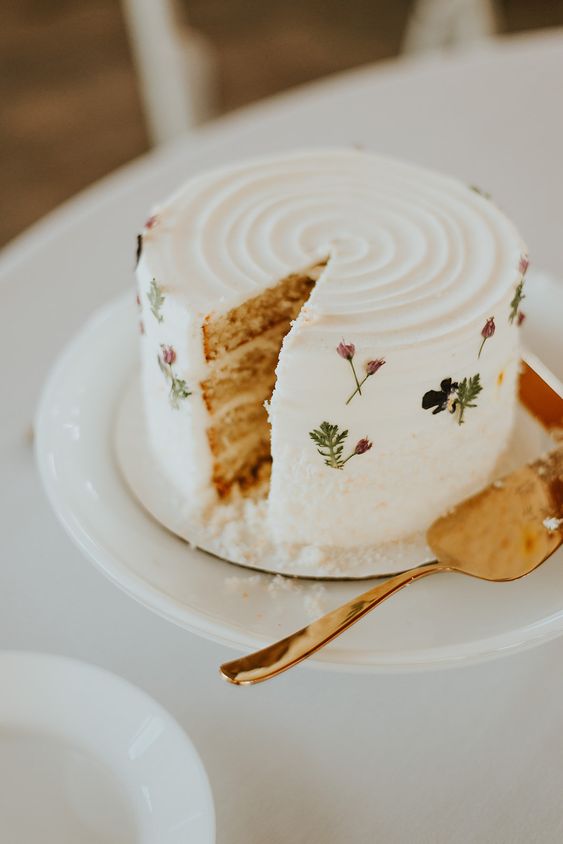 a white textured wedding cake decorated with only a bit of pressed blooms is a cool idea for spring and summer