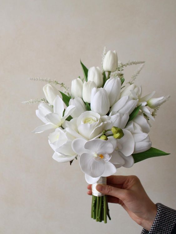 a white wedding bouquet of tulips, roses adn orchids is a chic and refined idea for a spring or summer wedding