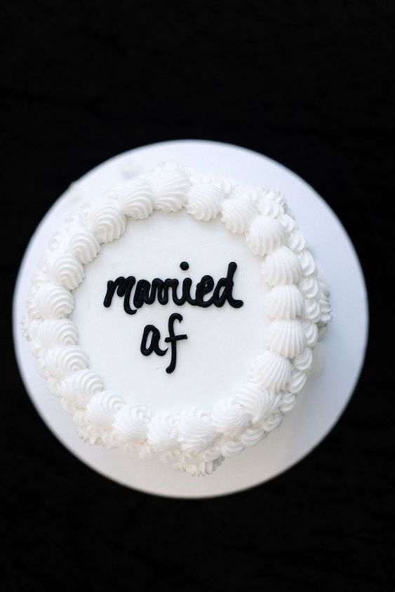 a white wedding cake decorated only with calligraphy is a super fun and non-traditional idea for any wedding