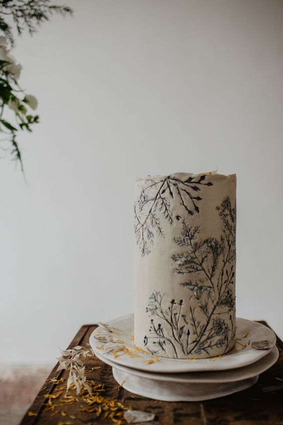 a white wedding cake with pressed greenery is a cool idea for a boho wedding