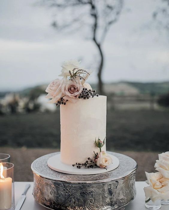 a white wedding cake with white and blush blooms and privet berries for a winter wedding done in neutrals