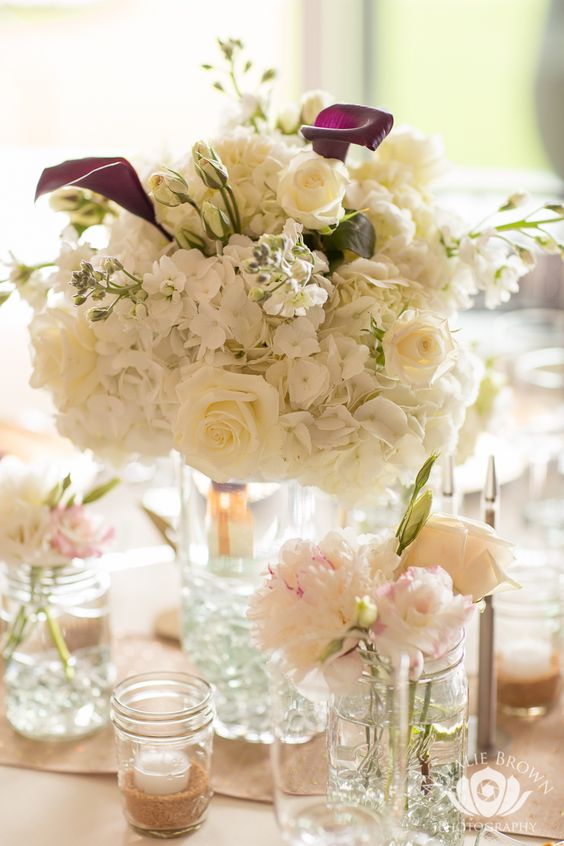 a white wedding centerpiece of roses and hydrangeas and deep purple callas is an amazing idea for neutral weddings
