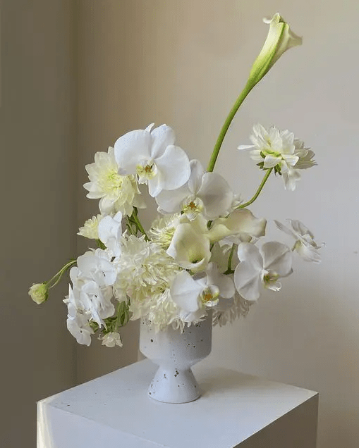 an airy white wedding centerpiece of callas, orchids and dahlias in a chic and cool idea for a white wedding