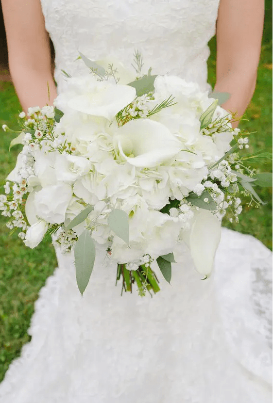 an all-white wedding bouquet of callas, roses, tulips, waxflower and some greenery is gorgeous for spring or summer