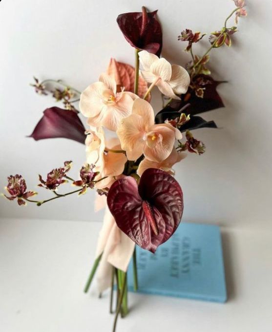 an exquisite wedding bouquet of peachy orchids, deep purple anthurium and callas and some blooming fillers for a fall wedding
