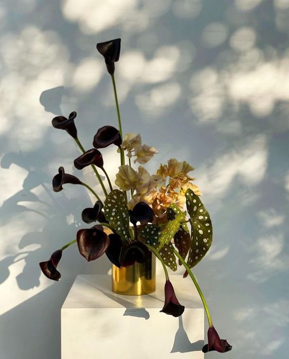 an exquisite wedding centerpiece of yellow sweet peas, deep purple callas and quirky leaves for a modern wedding