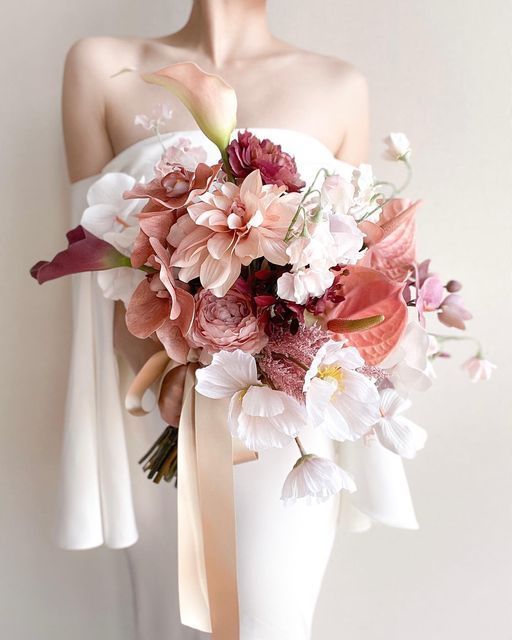 An eye catchy wedding bouquet with burgundy callas, anthuriums, roses and pink orchids and dahlias