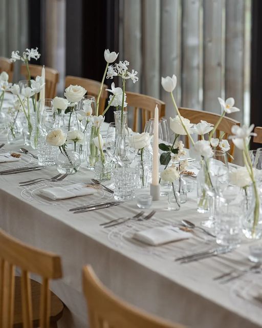 Beautiful cluster wedding centerpieces composed of clear vases and white blooms   tulips, roses and peony roses