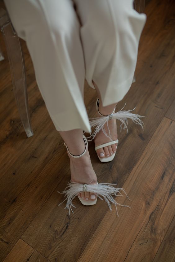 minimalist white wedding shoes accented with some feathers and embellishments will be a chic idea for a modern bridal look