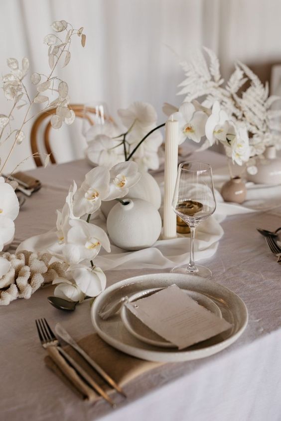 cluster white wedding centerpieces of orchids, lunaria and spray painted fenr leaves are amazing