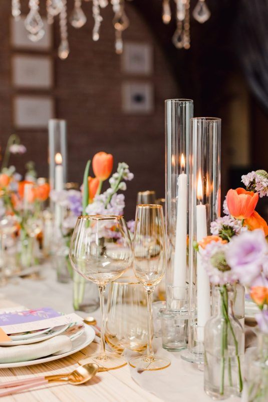 cool wedding centerpieces of orange tulips, freesias and lilac roses plus tall candles for a bright spring wedding