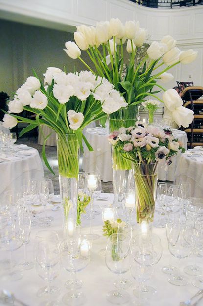 tall white wedding centerpieces of tulips and anemones plus candles around for a modern spring or summer wedding