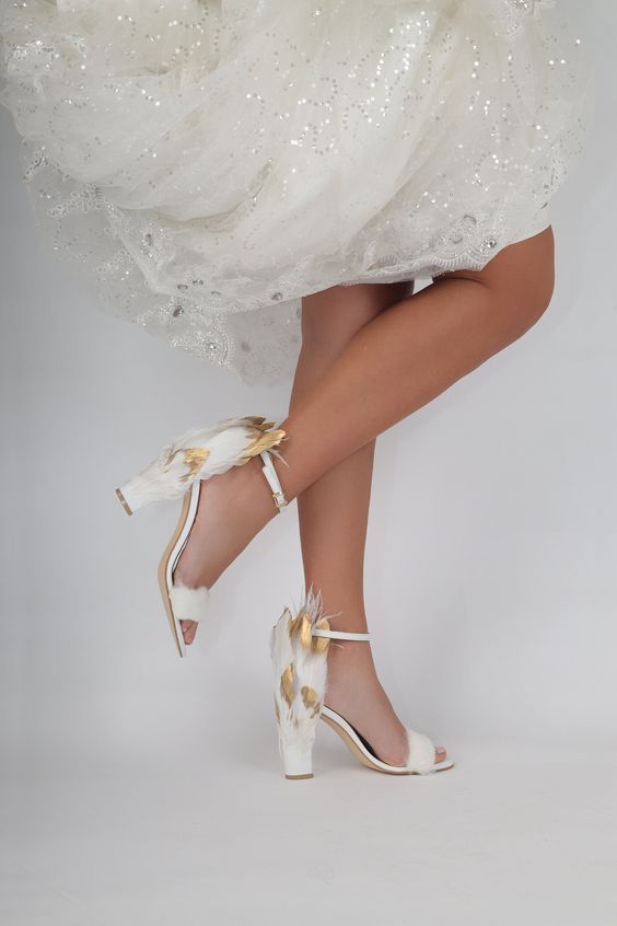 white wedding shoes with block heels and gilded feathers on the back are amazing for a unique bridal look