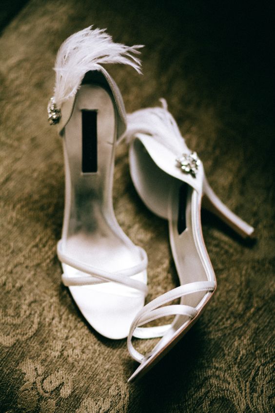 white wedding shoes with criss cross straps, embellishments and feathers are amazing for a glam and shiny wedding