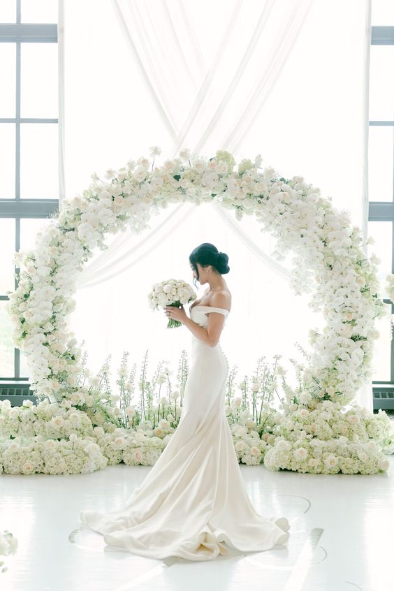 a round wedding arch covered with white orchids and roses is a cool and catchy solution that will make your space refined, special and chic