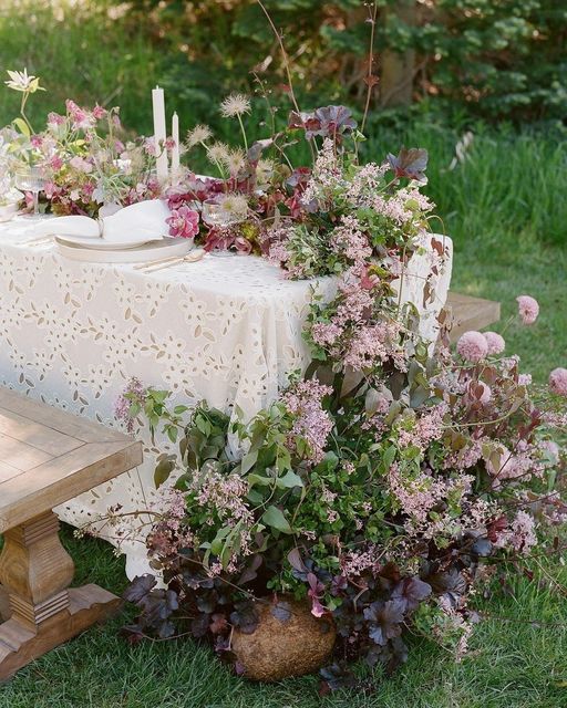 a beautiful and lush wedding centerpiece of pink and mauve blooms, greenery and dark foliage is a super catchy idea