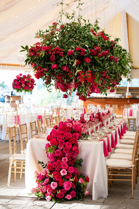 a beautiful and refined cascading rose wedding centerpiece of pink, hot pink and light pink roses and a greenery overhead installation