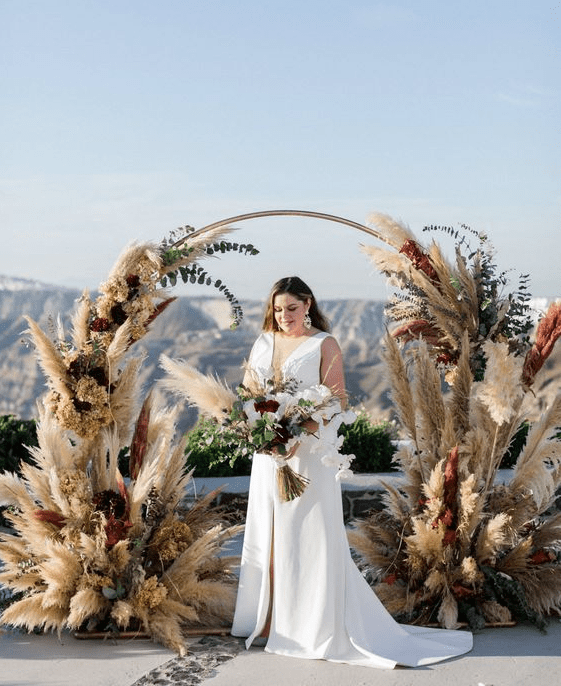 a beautiful boho round wedding arch with pampas grass and greenery and dried hydrangeas is a very lovely idea