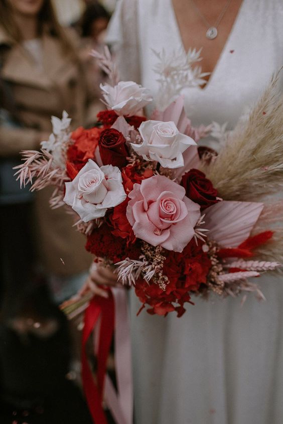 a beautiful colorful wedding bouquet of pink, white and red roses, pampas grass and some bright dried touches is a cool idea