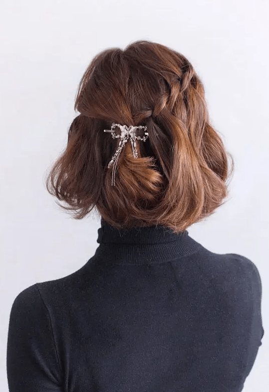 a beautiful half updo with a braid on one side and twist on the other, with waves down and a shiny hair piece