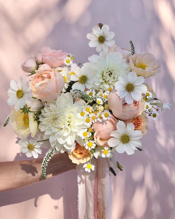 a beautiful summer wedding bouquet with white dahlias, cosmos, peachy peonies, chamomiles and astilbe