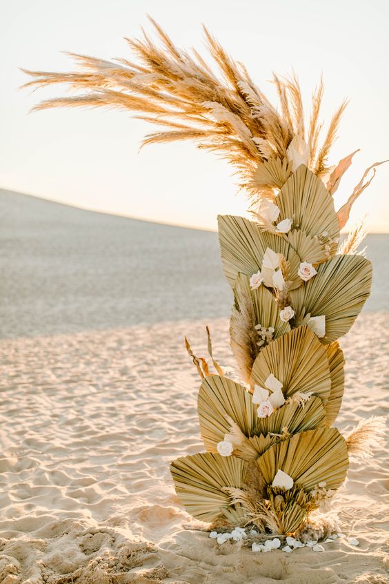 a boho wedding altar composed of pampas grass and fronds and blush and white roses is a cool idea for a beach boho wedding