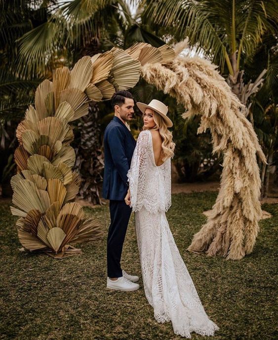 a boho wedding arch covered with fronds and pampas grass is a cool decoration for a tropical or just summer boho wedding
