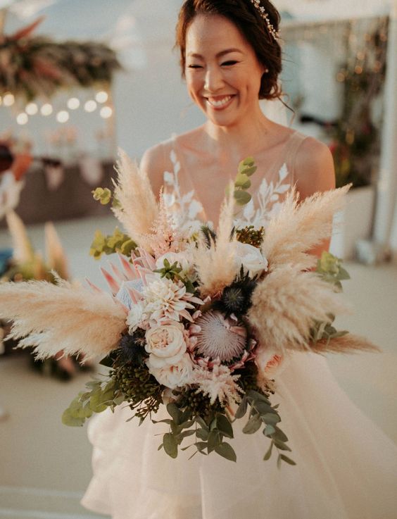 a boho wedding bouquet of blush blooms, king proteas, pampas grass and greenery is a cool solution for a boho wedding