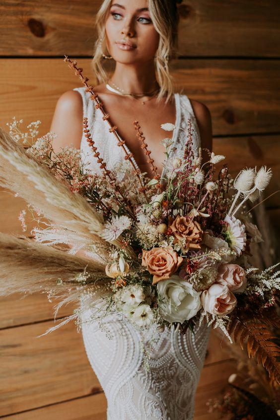 a boho wedding bouquet of pampas grass and dried leaves, neutral and orange blooms, fresh and dried ones