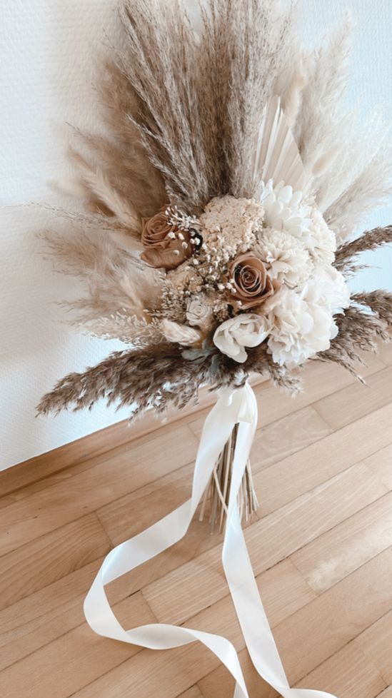 a boho wedding bouquet of pampas grass, coffee-colored and white roses and white ribbon is a cool idea for a neutral wedding
