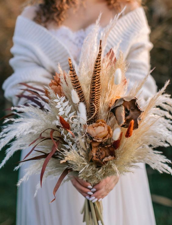 a boho wedding bouquet of pampas grass, feathers, dried blooms and bunny tails is amazing for a boho wedding