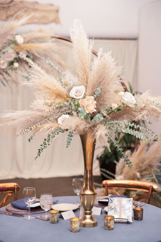 a boho wedding centerpiece of a brass vase, neutral roses, greenery and pampas grass is a cool and catchy idea