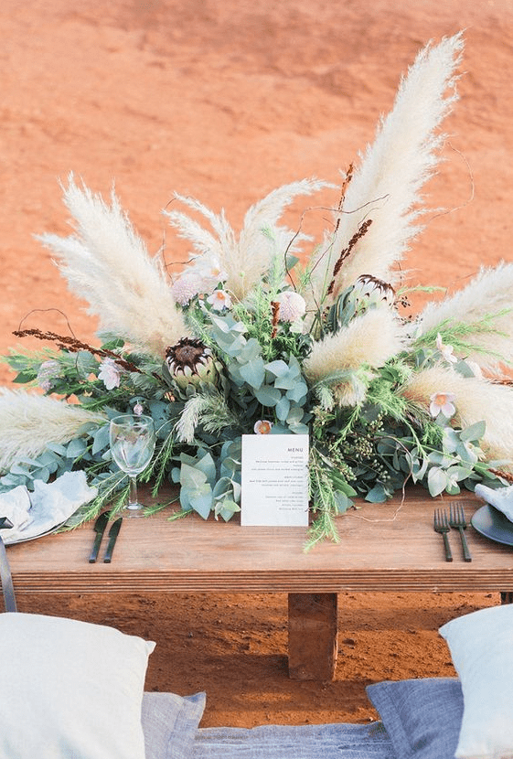a boho wedding centerpiece of greenery, bright blooms and lush pampas grass
