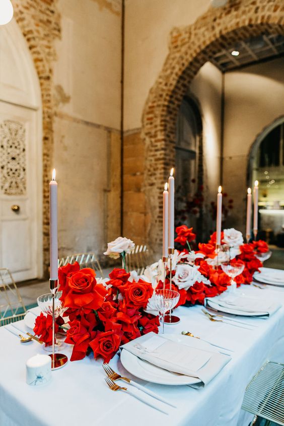 a bold and lush wedding centerpiece of blush and red orses and blush candles is amazing for a bright wedding