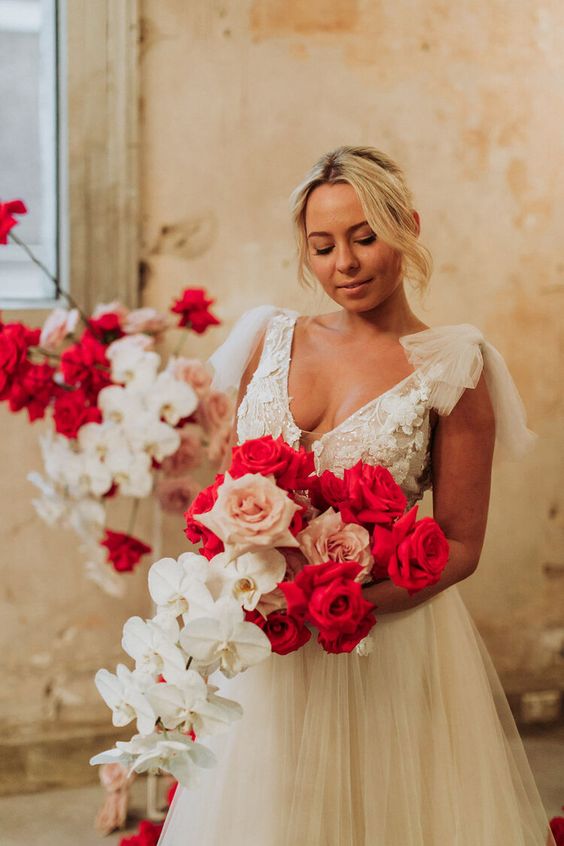 a bold cascading wedding bouquet of blush and red roses and white orchids is absolutely fantastic