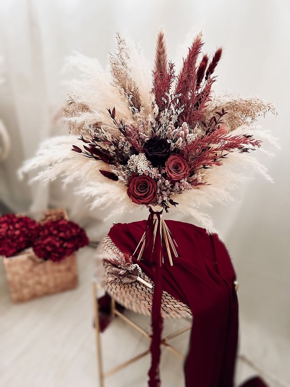 a bold fall wedding bouquet of pampas grass in various shades, with red and dark roses, some fillers for a fall wedding