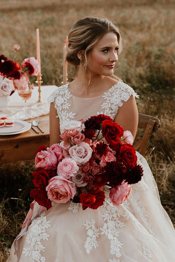 a bold fall wedding bouquet of red and pink roses, burgundy dahlias and some fillers is stunning