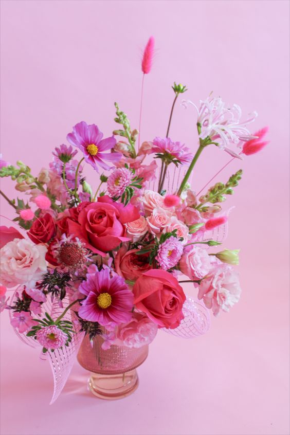 a bold wedding centerpiece of hot pink cosmos, red roses, various pink, blush and hot pink blooms