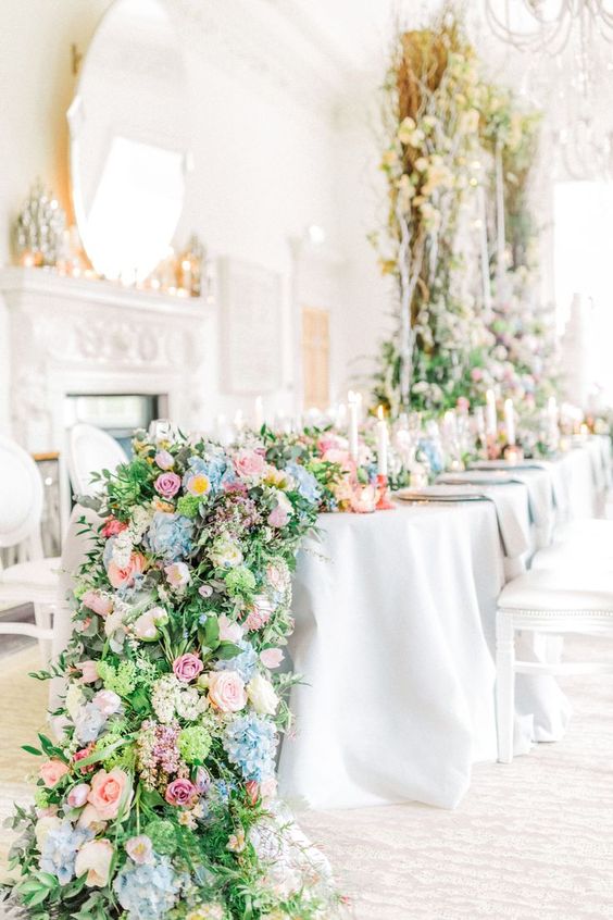 a bright cascading wedding centerpiece of greenery, pink, blue and yellow blooms and foliage is wow