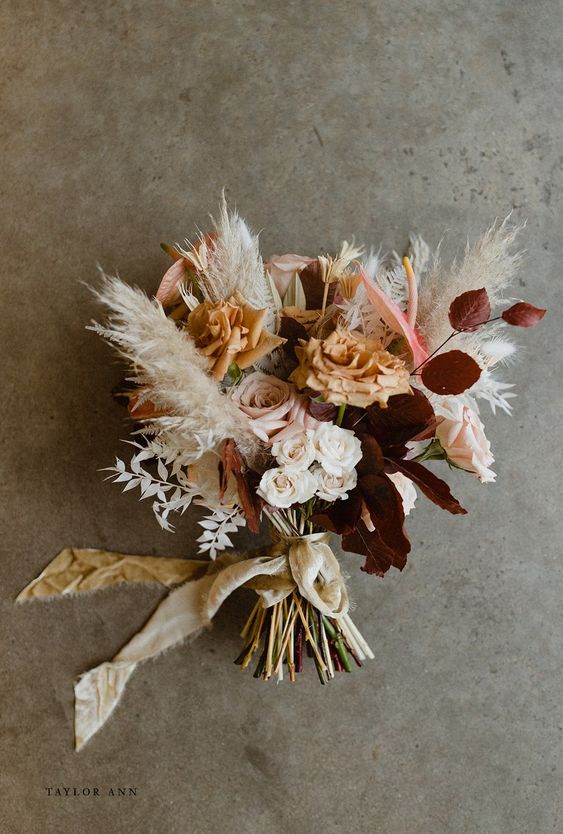 a bright fall wedding bouquet of white, blush and rust roses, bold foliage and pampas grass and pink anthuriums is wow