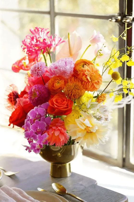 a bright gradient floral wedding centerpiece from red to rust, hot pink and yellow with a unique structure and shape