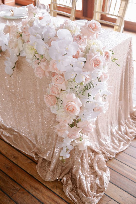 a cascading blush and white wedding centerpiece of roses and orchids is a cool decor idea for a glam and chic wedding