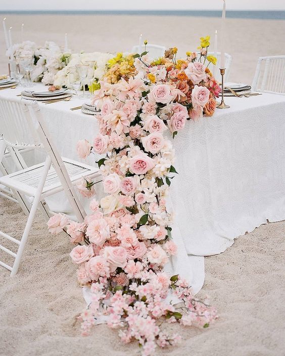 A cascading ombre wedding centerpiece from white to yellow and pink, with roses and some other blooms is jaw dropping