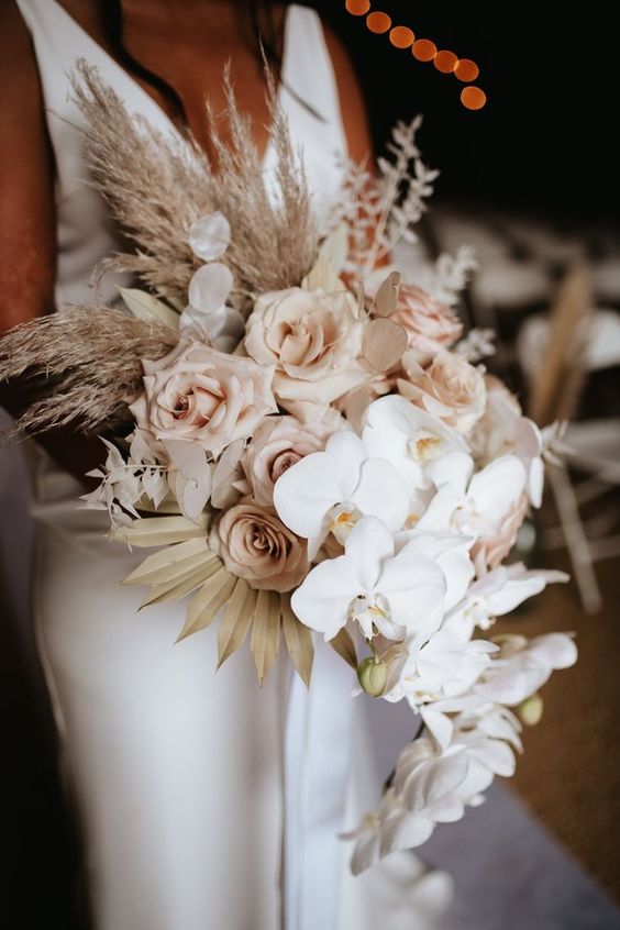 a cascading wedding bouquet of blush roses, white orchids, pampas grass and fronds is a very refined arrangement